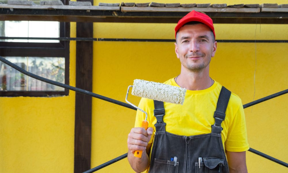 Pintor profesional con rodillo pintando zonas comunes en Valencia