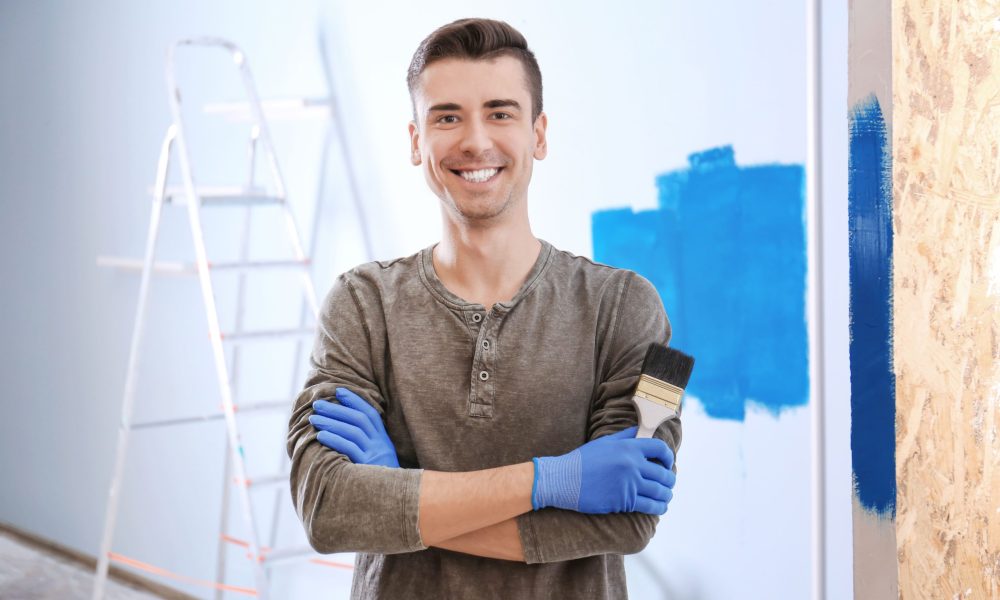 Operario alisando y pintando una pared interior en Valencia